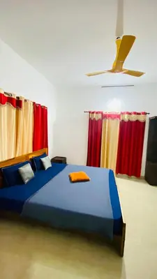a bedroom with a blue bed and red curtains at The Wayanad Stays in Kalpetta