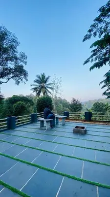 a person sitting on a bench on a roof at The Wayanad Stays in Kalpetta