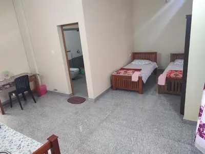 a room with two beds and a table and a mirror at Bridgettine Paradise in Sultan Bathery