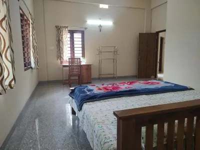 a bedroom with a bed and a table in it at Bridgettine Paradise in Sultan Bathery