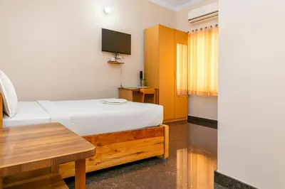 a bedroom with a bed and a table and a tv at Stayz Royale - Mysuru near Mysuru Palace in Mysore