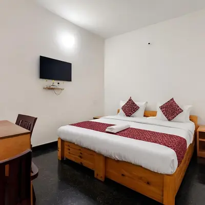 a bedroom with a bed and a desk and a television at Stayz Royale - Mysuru near Mysuru Palace in Mysore