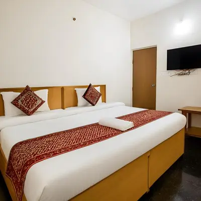 a bedroom with a large bed with a television on the wall at Stayz Royale - Mysuru near Mysuru Palace in Mysore