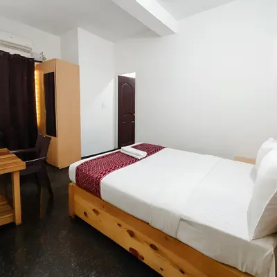 a bedroom with a white bed and a desk and a table at Stayz Royale - Mysuru near Mysuru Palace in Mysore