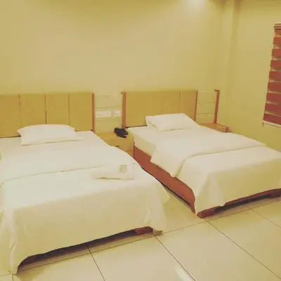 a bedroom with two beds with white sheets at Neom Inn in Wayanad