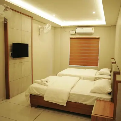 a bedroom with two beds and a television in it at Neom Inn in Wayanad