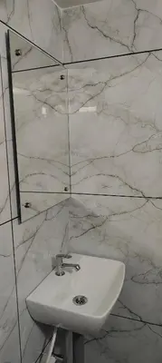 a white sink in a bathroom with marble walls at Ivory Suites Meadows in Kozhikode