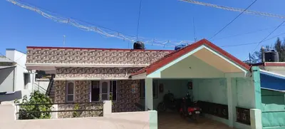 a small brick house with a front porch at Jay bahadur Cottages and home stay in Ooty
