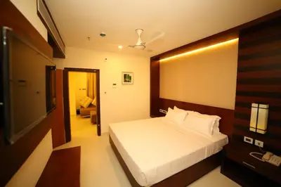 a bedroom with a bed and a living room at Vavas Inn & Suites in Perintalmanna