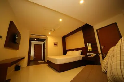 a hotel room with a bed and a bathroom at Vavas Inn & Suites in Perintalmanna