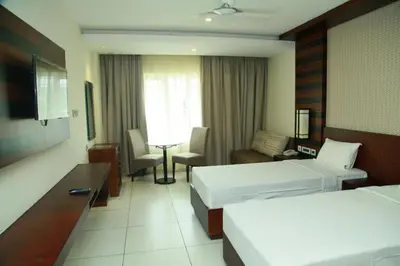 a hotel room with two beds and a living room at Vavas Inn & Suites in Perintalmanna