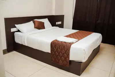 a bedroom with a large bed with brown and white sheets at Gokulam suits guruvayur in Guruvāyūr