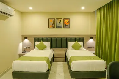 two beds in a hotel room with green curtains at Chaliyar Resorts