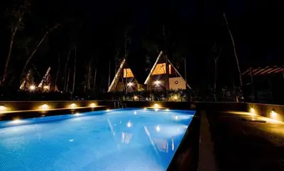 a large swimming pool with lights in front of a house at ivaana resorts mysore in Mysore