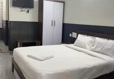 a bedroom with a white bed with a tv on it at Hotel Alka Inn Residency Wayanad in Sultan Bathery