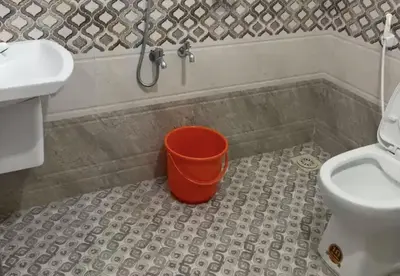 a bathroom with a bucket in the tub next to a toilet at Hotel Alka Inn Residency Wayanad in Sultan Bathery