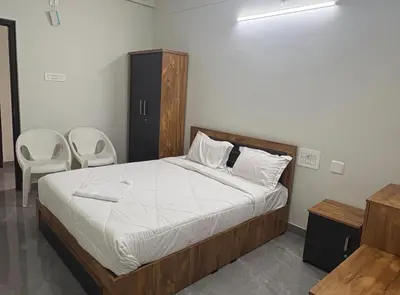 a bedroom with a bed and two chairs in it at Hotel Alka Inn Residency Wayanad in Sultan Bathery