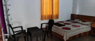 a bedroom with a bed and a table and chairs at hilldown cottage in Ooty