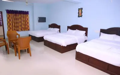 a bedroom with two beds and a table and chairs at hilldown cottage in Ooty