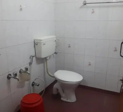 a bathroom with a white toilet in a stall at hilldown cottage in Ooty