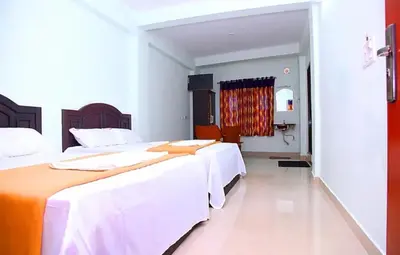 two beds in a room with white and orange sheets at hilldown cottage in Ooty