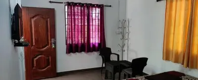a room with a door and some chairs and a window at hilldown cottage in Ooty