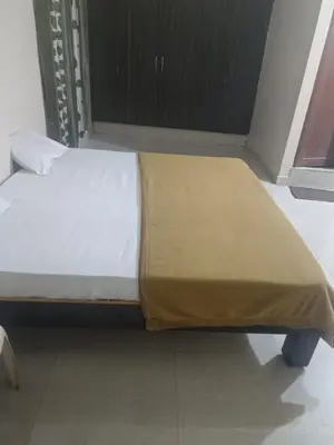 a bed with a yellow blanket on top of it at Shreyas Residency in Mysore