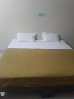 a large bed with white sheets and pillows on it at Shreyas Residency in Mysore