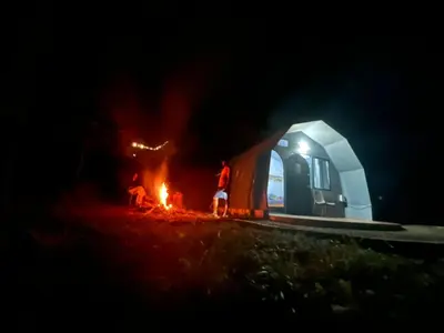 two people standing around a fire in front of a tent at Spirit of the Wild Mountain Retreat in Palakkad