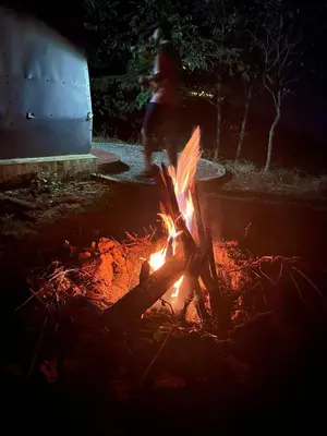 a person is walking around a fire in a yard at Spirit of the Wild Mountain Retreat in Palakkad