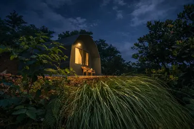 a small house on top of a grassy hill at night at Spirit of the Wild Mountain Retreat in Palakkad
