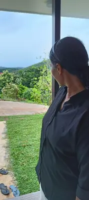 a woman looking out of a window at the grass at Metta Heaven Farm Resort in Kodenchery