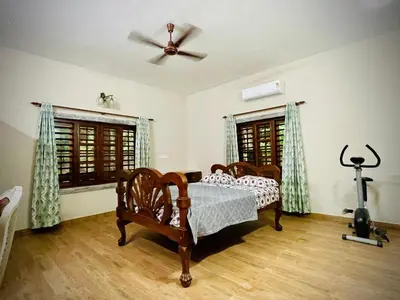 a bedroom with a bed and a ceiling fan at Lush Orchard in Kizhake Chālakudi