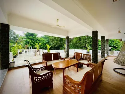 a living room with a table and chairs at Lush Orchard in Kizhake Chālakudi