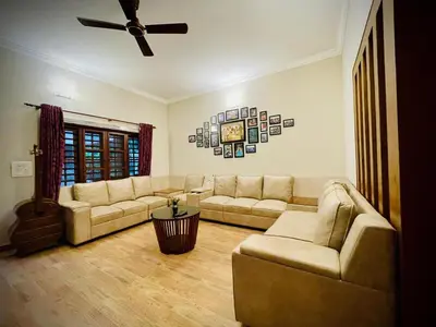 a living room with two couches and a ceiling fan at Lush Orchard in Kizhake Chālakudi