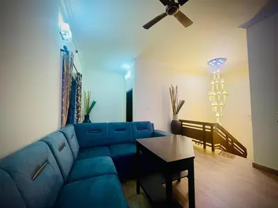a living room with a blue couch and a ceiling fan at Lush Orchard in Kizhake Chālakudi