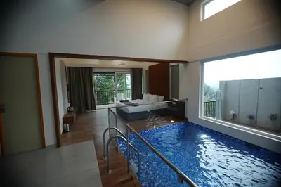 a living room with a large swimming pool in a house at Ymoon Mountain Resort Wayanad in Koroth