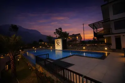 a swimming pool at night with a building at Ymoon Mountain Resort Wayanad in Koroth