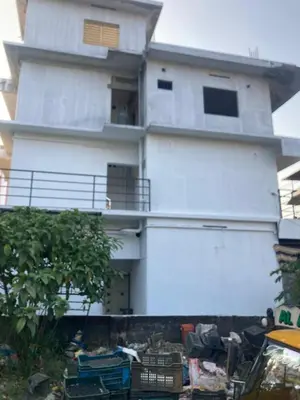 a white building with a lot of trash in front of it at Valiyaveettile in Alwaye