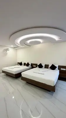 two beds in a large room with a ceiling at SKB Suites in Mysore