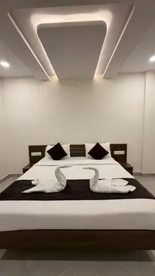 a bedroom with a bed with white sheets and pillows at SKB Suites in Mysore