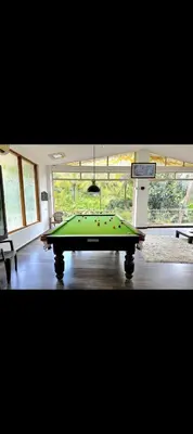 a pool table in a room with a window at The 77 estate stay coorg in Suntikoppa