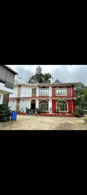 a large red and white building with windows at The 77 estate stay coorg in Suntikoppa