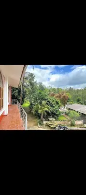 a balcony of a house with a view of a park at The 77 estate stay coorg in Suntikoppa