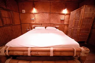 a bedroom with a large bed with white sheets at Bali bamboo in Padinjarathara