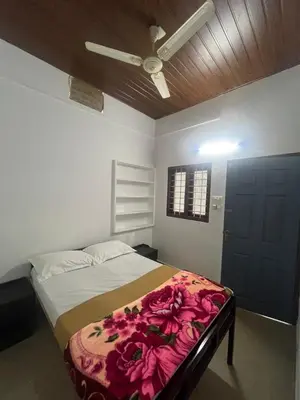 a bedroom with a bed with pink flowers on it at Pookode Service Villa in Vythiri