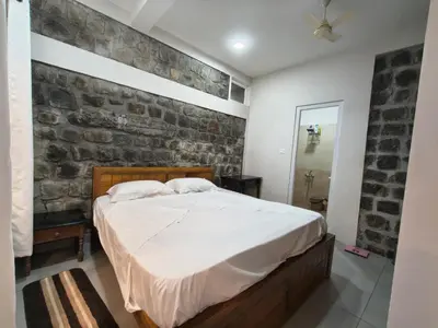 a bedroom with a bed and a brick wall at Sunflower Villa Cottage Coonoor in Coonoor