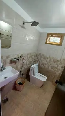 a bathroom with a white toilet and a sink at Caramel stay in Marayoor