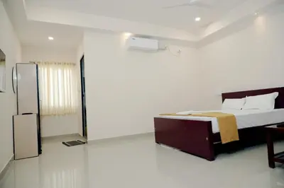 a white bedroom with a bed and a mirror at Amritha Lodge in Kollengode