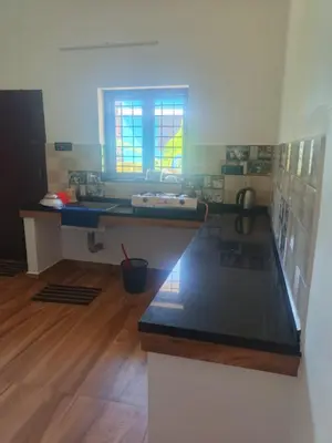 a kitchen with a counter top in a room at Sandal Homestay in Marayoor